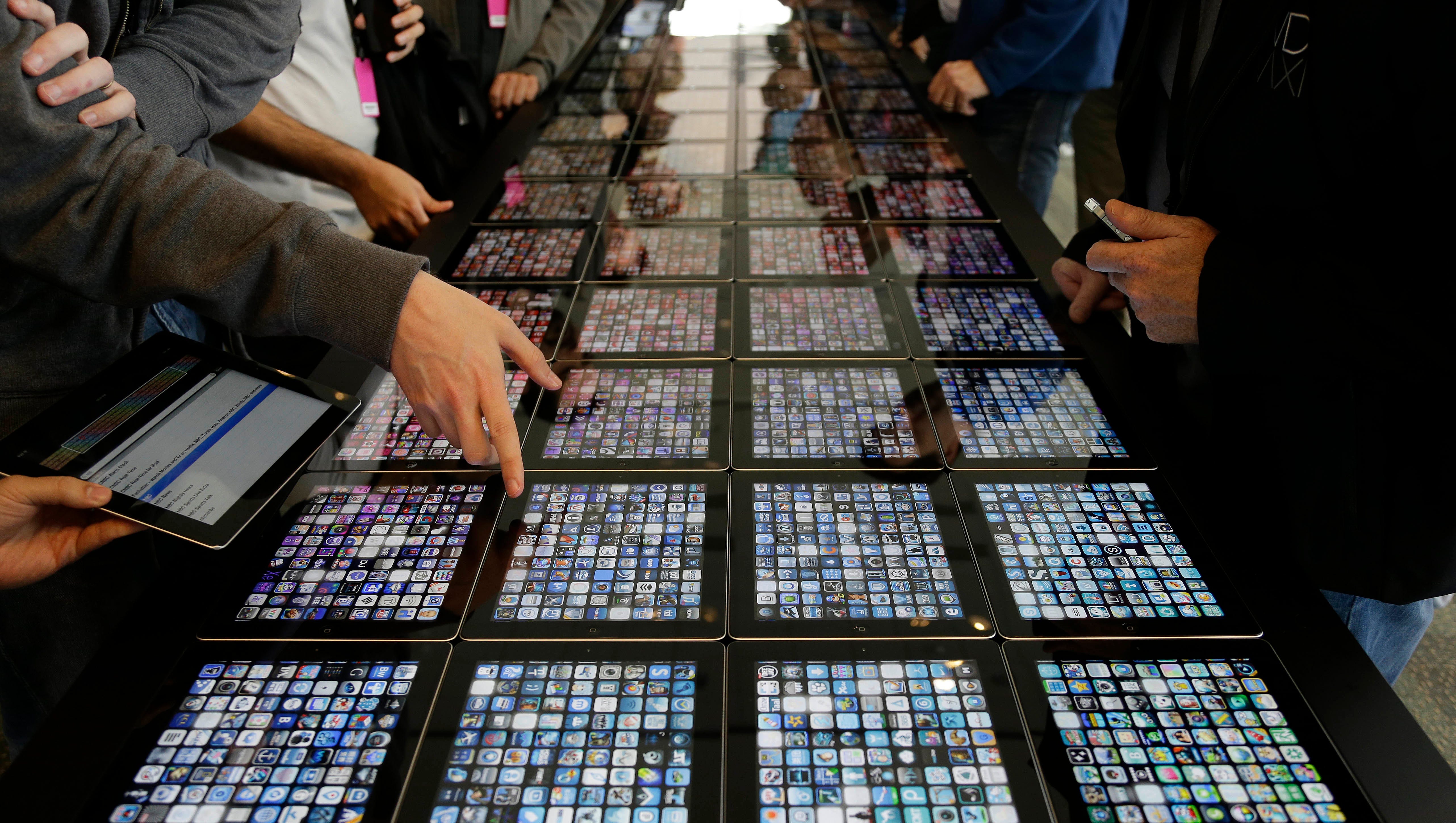In this June 10, 2013, file photo, developers look over new apps being displayed on iPads at the Apple Worldwide Developers Conference in San Francisco.