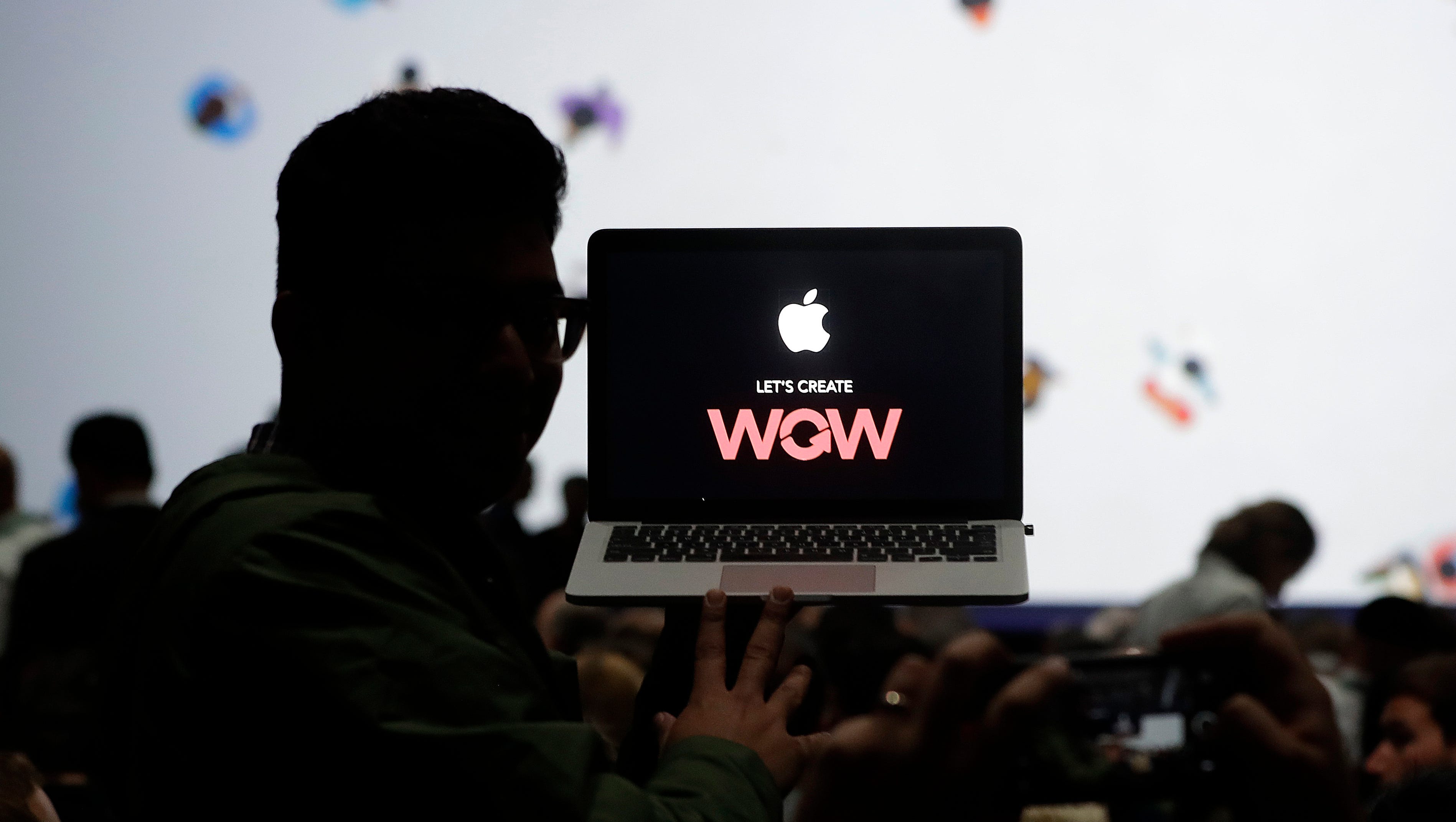 A man holds up a laptop computer before an announcement of new products at the Apple Worldwide Developers Conference in San Jose, Calif. onJune 5, 2017.