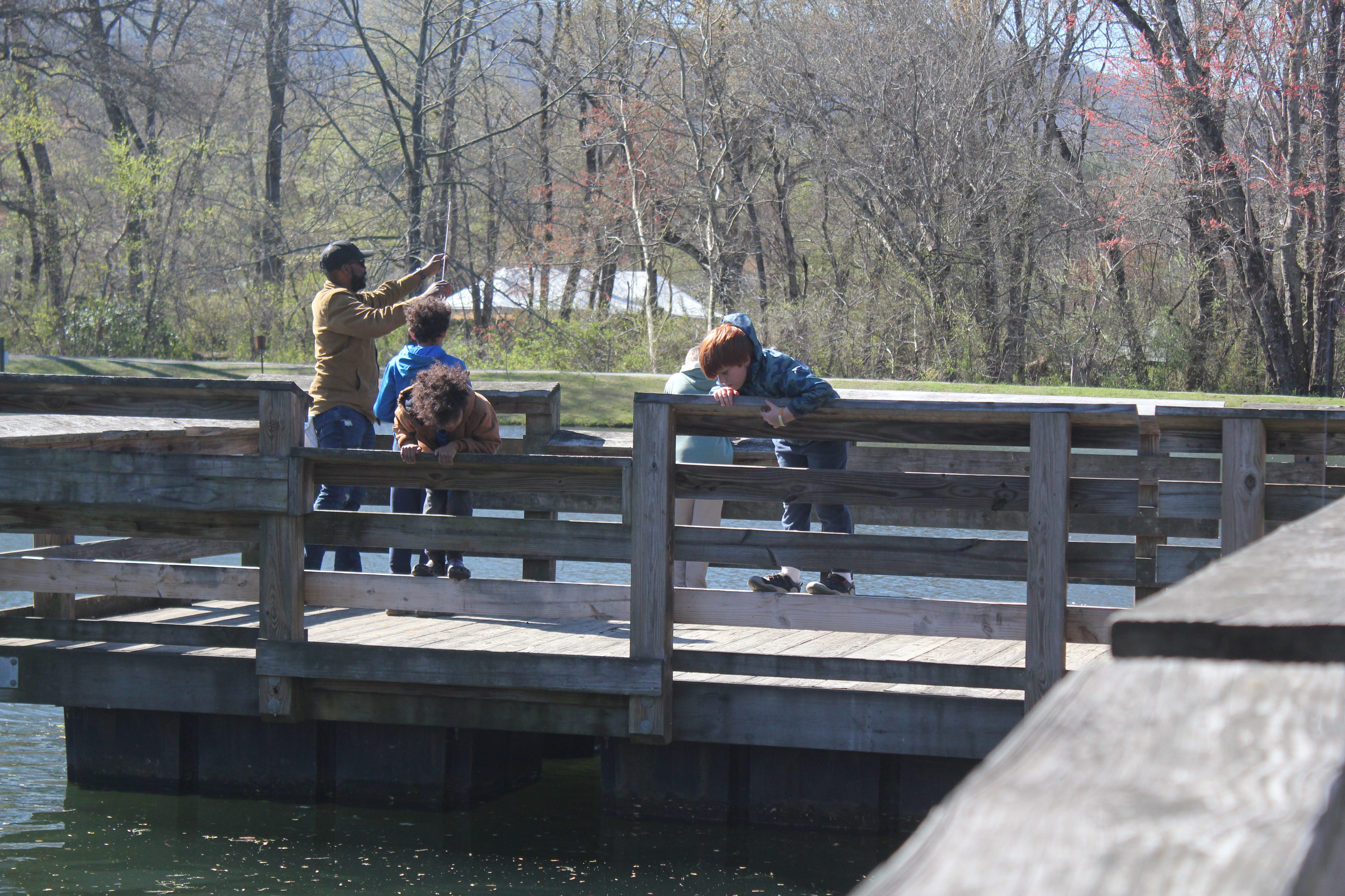 Kids look for fish over the side of the pier at Buncombe County Parks and Recreation's kids fishing tournament at Charles D. Owen Park April 13, 2024.